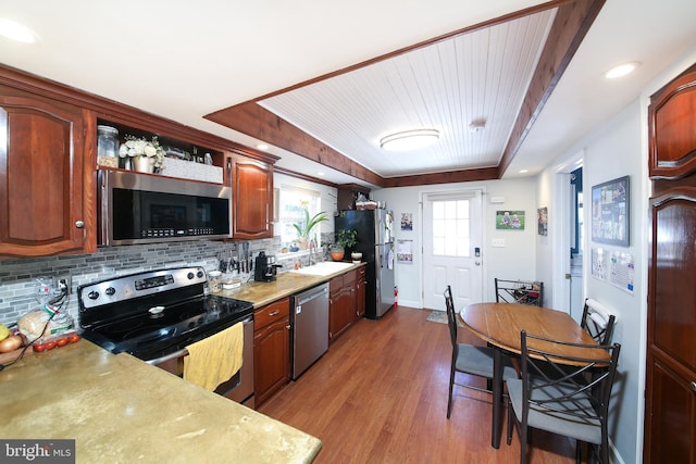 kitchen featuring appliances with stainless steel finishes, dark hardwood / wood-style flooring, a raised ceiling, and tasteful backsplash