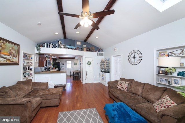 living room featuring ceiling fan, vaulted ceiling with skylight, built in features, and wood-type flooring