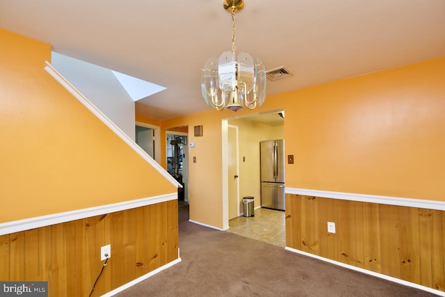 unfurnished dining area with light colored carpet and wooden walls