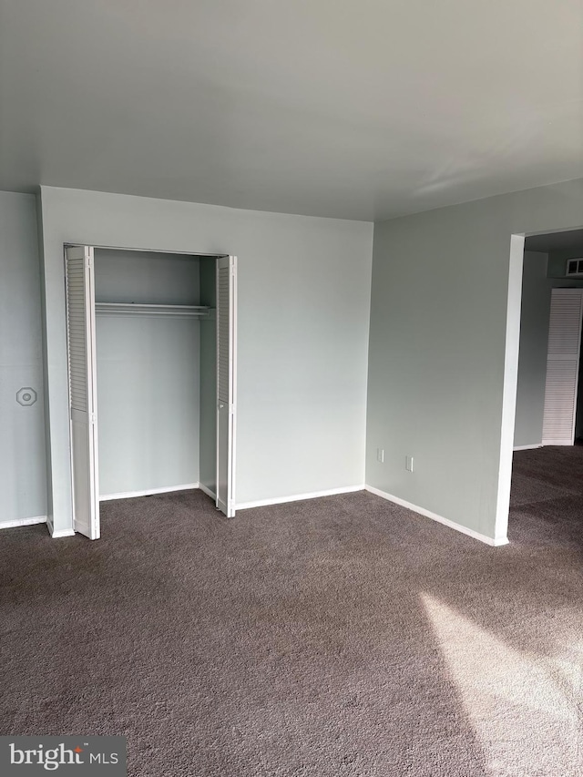 unfurnished bedroom featuring a closet and dark colored carpet