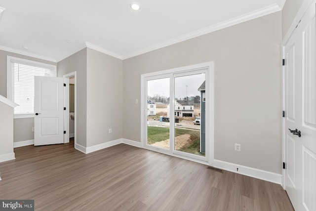 spare room featuring plenty of natural light, ornamental molding, and light hardwood / wood-style flooring