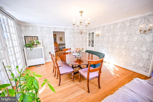 dining room featuring light hardwood / wood-style floors, crown molding, and a notable chandelier