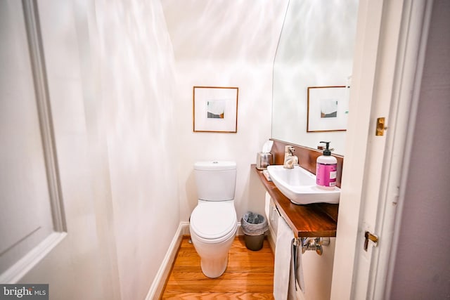 bathroom with sink, hardwood / wood-style floors, and toilet