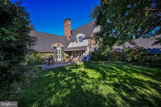 back of property featuring a patio area and a lawn