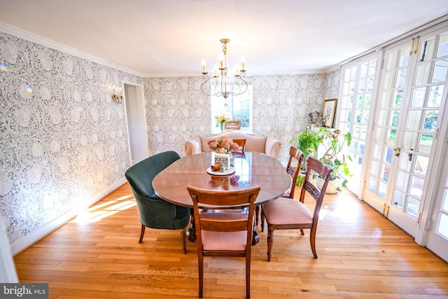 dining space featuring a notable chandelier, french doors, ornamental molding, and light hardwood / wood-style floors