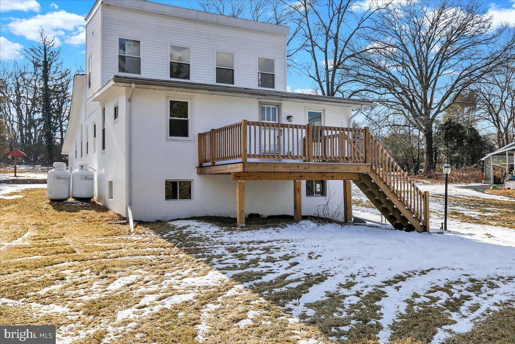 snow covered rear of property featuring a wooden deck