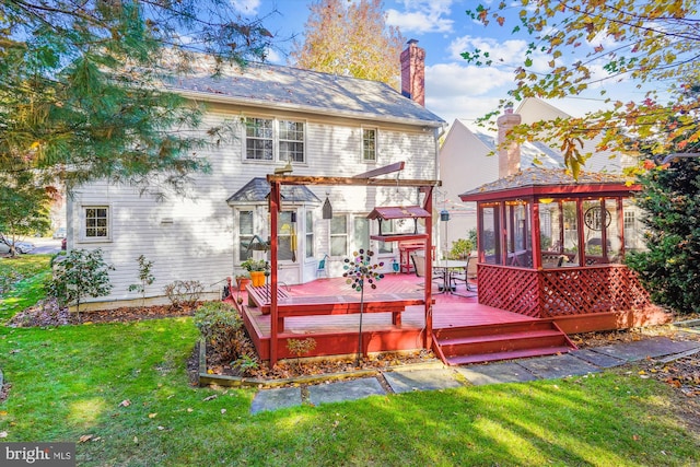 rear view of property featuring a deck, a chimney, a lawn, a sunroom, and a pergola