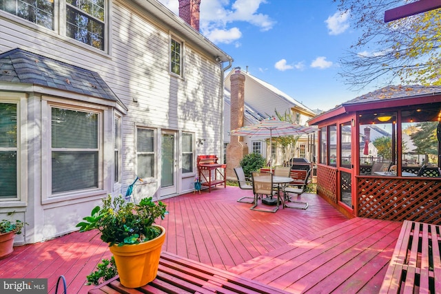 wooden deck featuring a sunroom and outdoor dining area