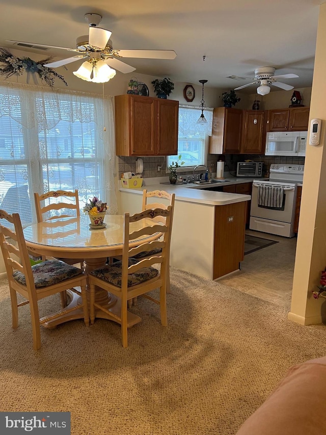 kitchen with tasteful backsplash, hanging light fixtures, white appliances, and kitchen peninsula