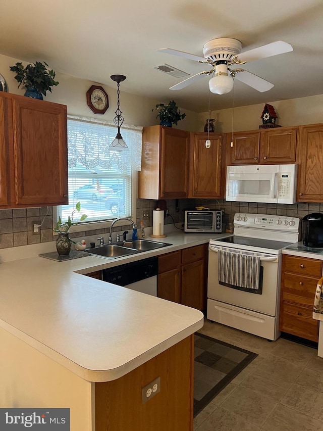 kitchen with sink, white appliances, hanging light fixtures, tasteful backsplash, and kitchen peninsula