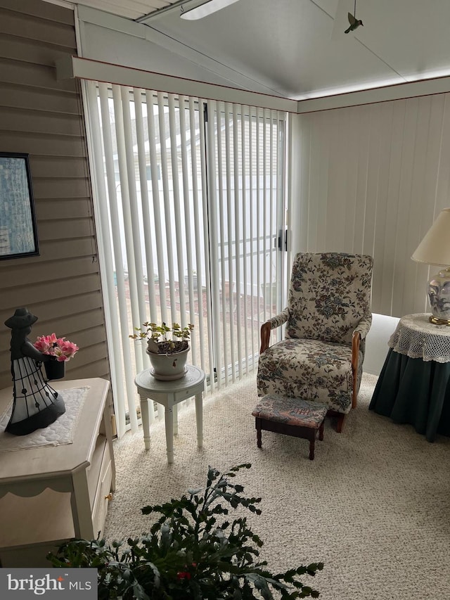 sitting room featuring carpet floors and wooden walls