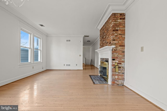 unfurnished living room with ornamental molding, a brick fireplace, and light wood-type flooring