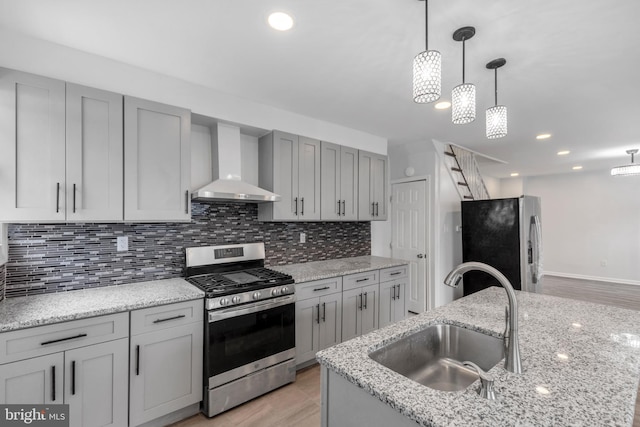 kitchen featuring sink, wall chimney range hood, gray cabinets, stainless steel appliances, and backsplash