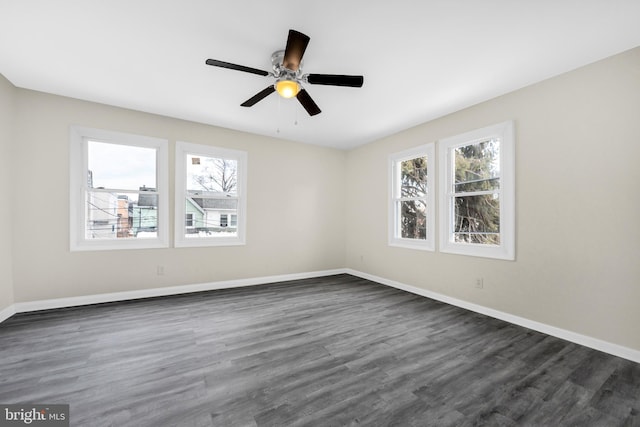 empty room featuring plenty of natural light, dark wood-type flooring, and ceiling fan