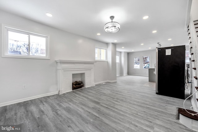 unfurnished living room featuring a barn door, a chandelier, and light hardwood / wood-style flooring