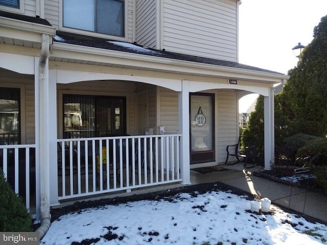 snow covered property entrance featuring a porch