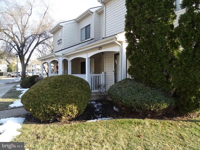 view of side of property featuring a lawn and covered porch