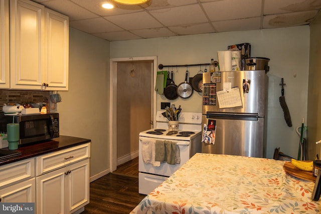 kitchen with dark wood-type flooring, stainless steel appliances, a drop ceiling, and white cabinets