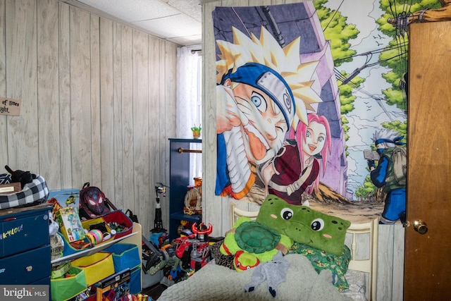 playroom with wooden walls and a drop ceiling