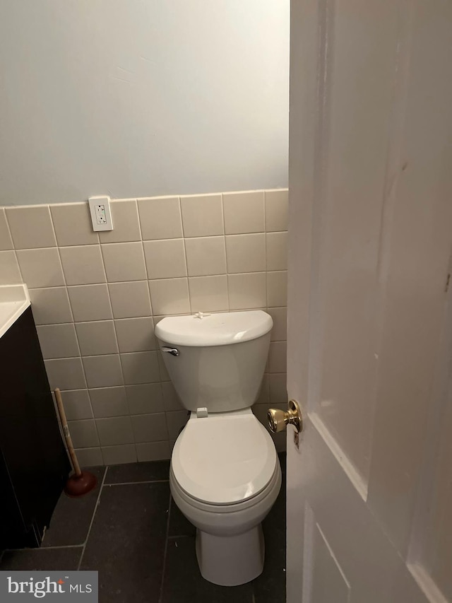 bathroom featuring tile patterned floors, tile walls, toilet, and vanity