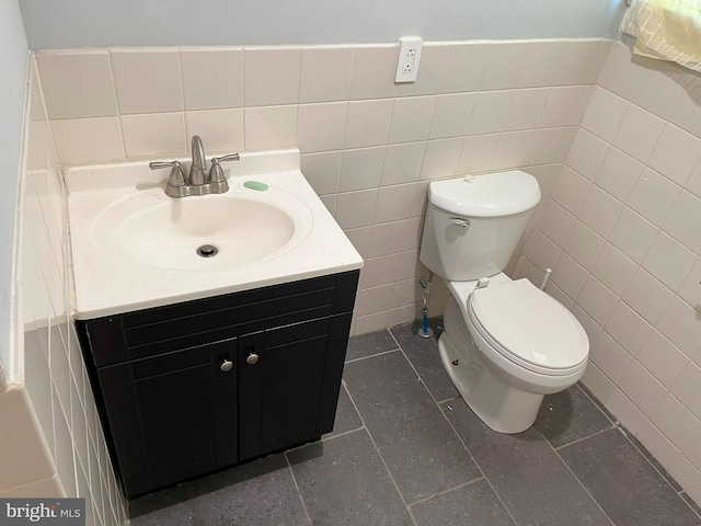 bathroom featuring vanity, toilet, tile walls, and tile patterned flooring