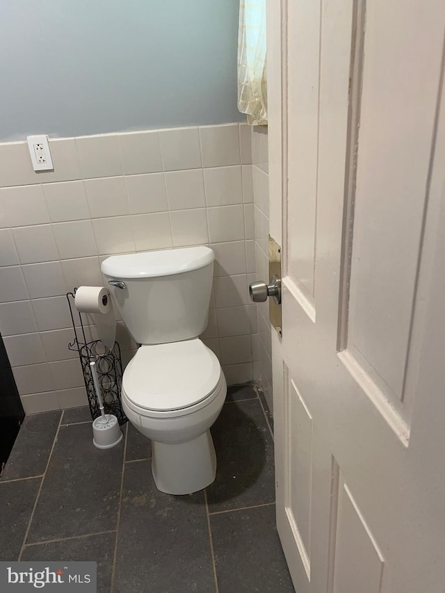 bathroom with toilet and tile walls