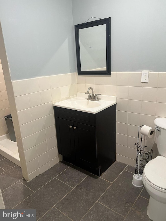 bathroom with tile patterned floors, tile walls, toilet, and vanity