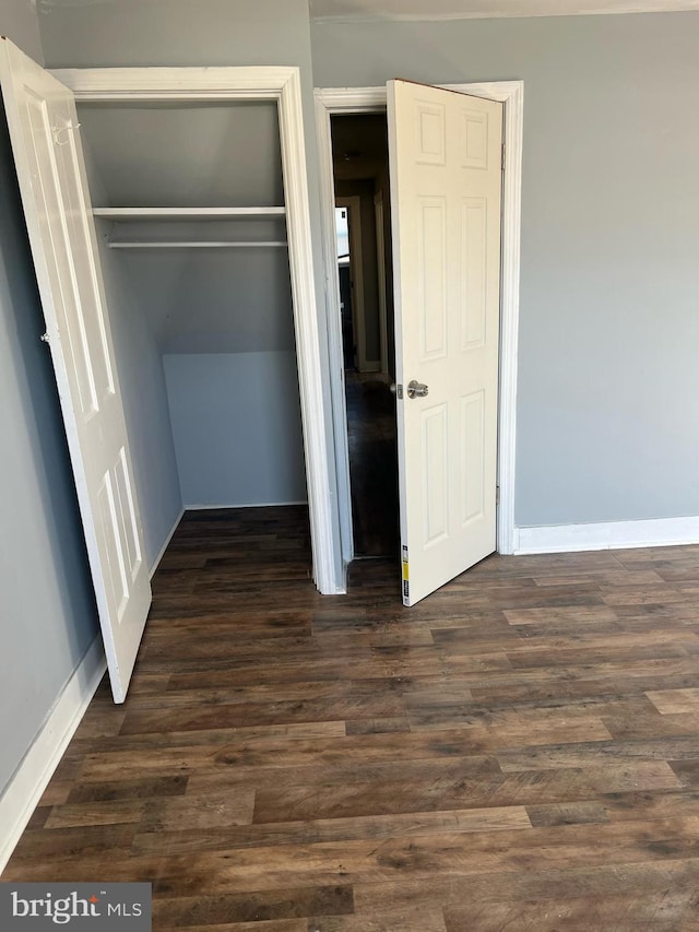 unfurnished bedroom featuring dark hardwood / wood-style flooring and a closet