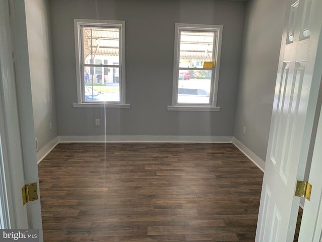 spare room featuring a healthy amount of sunlight and dark wood-type flooring