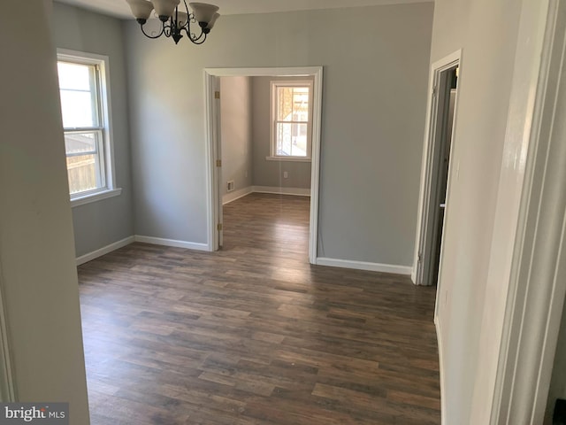 spare room with a chandelier and dark hardwood / wood-style flooring