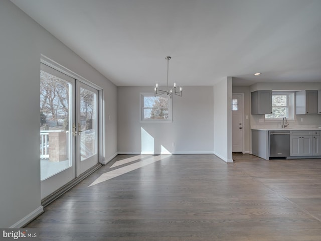 unfurnished dining area featuring french doors, a chandelier, light hardwood / wood-style floors, and sink