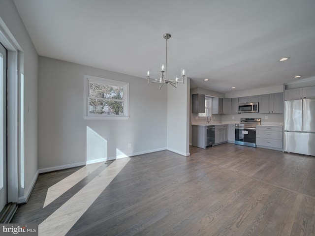 kitchen featuring pendant lighting, sink, gray cabinetry, dark hardwood / wood-style flooring, and stainless steel appliances