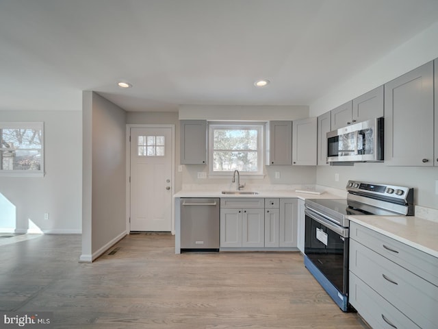 kitchen featuring light wood-type flooring, appliances with stainless steel finishes, sink, and gray cabinetry