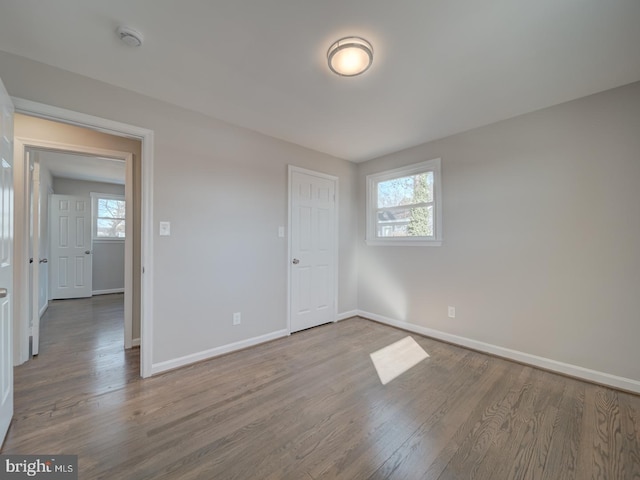 unfurnished bedroom with multiple windows and hardwood / wood-style flooring