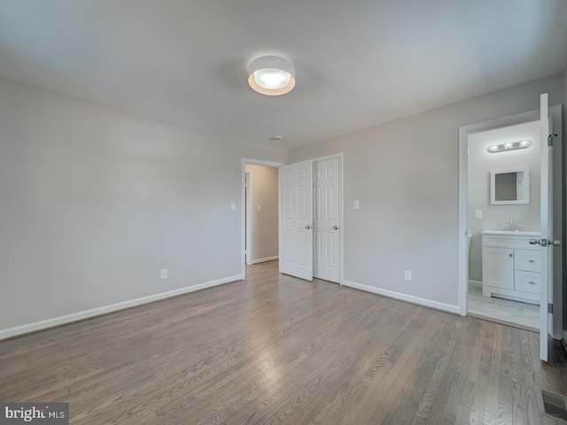 unfurnished bedroom with connected bathroom, light hardwood / wood-style floors, and sink