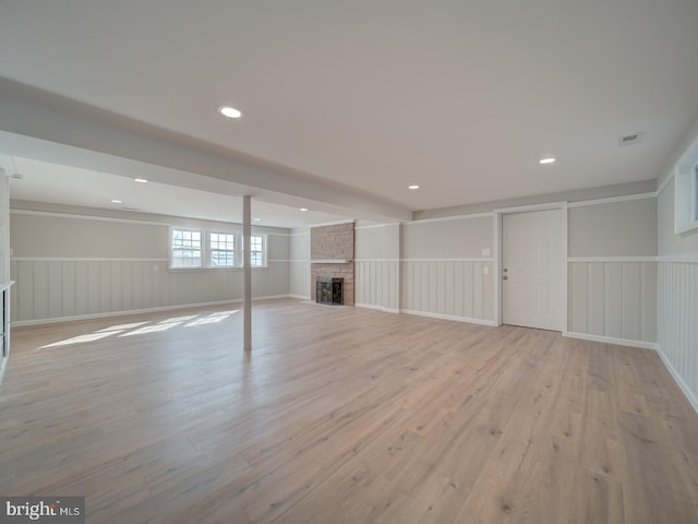 basement with a brick fireplace and light wood-type flooring