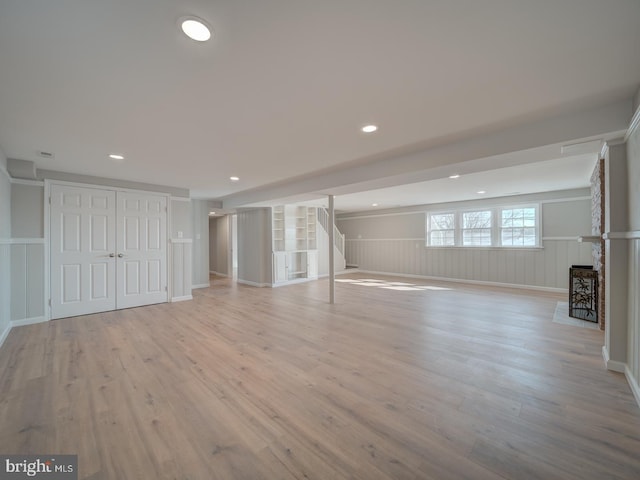 unfurnished living room with a fireplace, light hardwood / wood-style floors, and built in shelves