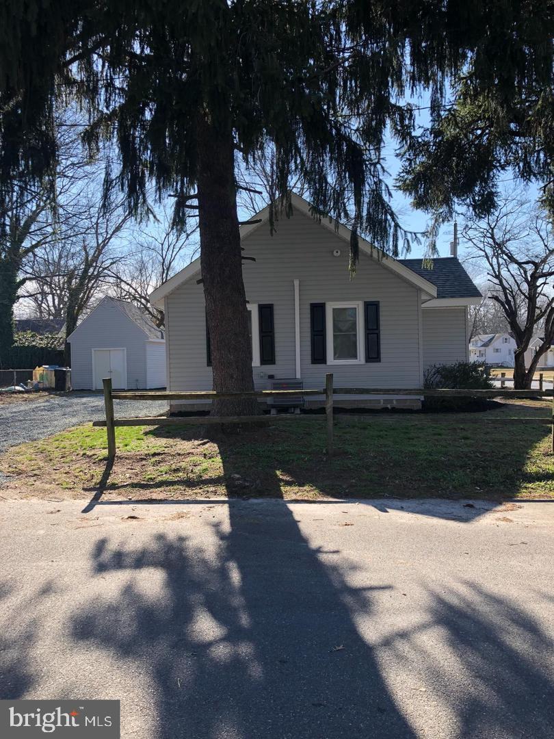 view of front of house featuring a garage, a front yard, and an outbuilding