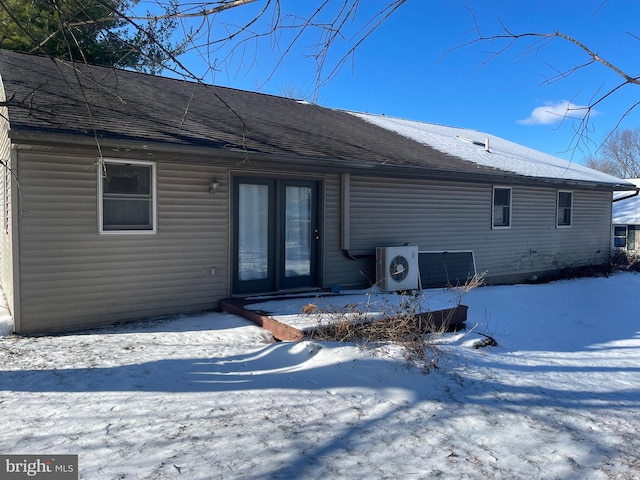 snow covered back of property featuring ac unit