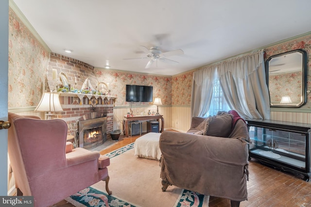 living room featuring ceiling fan, wood-type flooring, and a brick fireplace