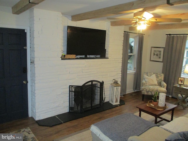 living room featuring ceiling fan, a fireplace, beamed ceiling, and hardwood / wood-style floors