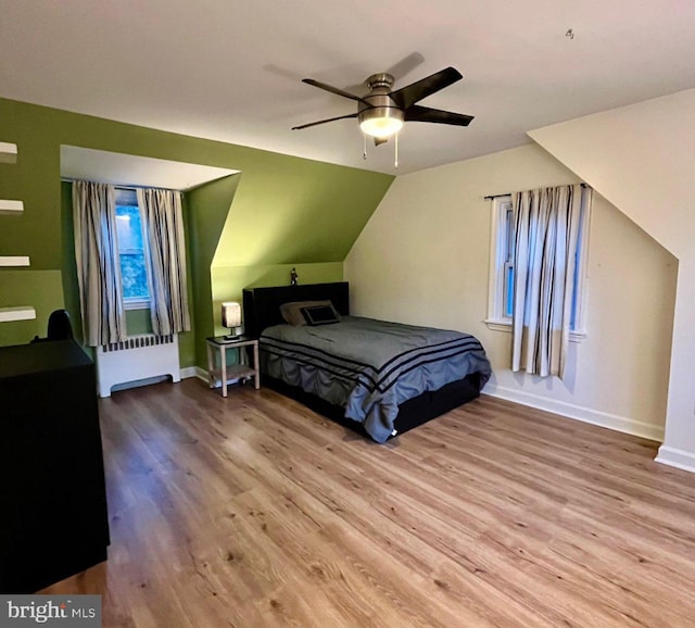 bedroom featuring ceiling fan, light wood-type flooring, radiator heating unit, and lofted ceiling