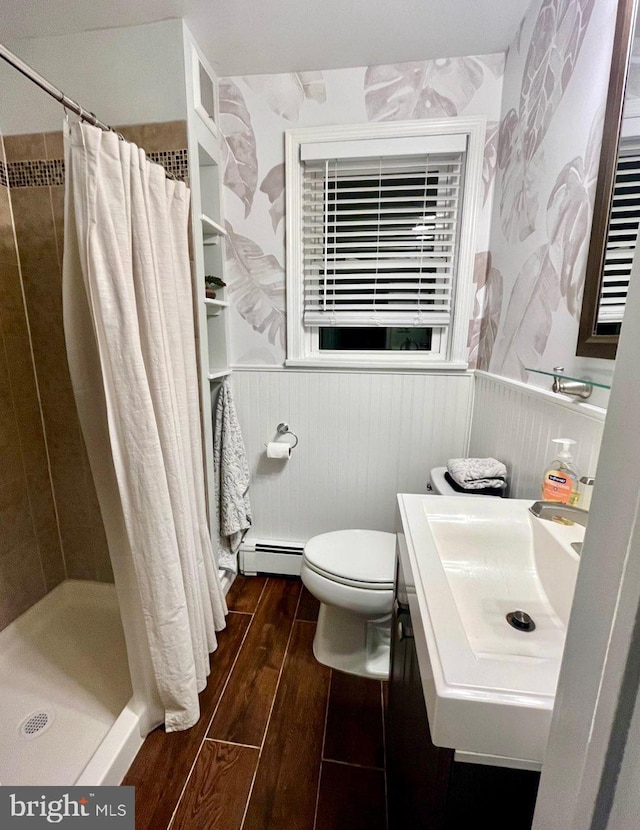 bathroom featuring toilet, a baseboard heating unit, a shower with curtain, sink, and wooden walls