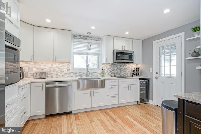 kitchen with white cabinets, beverage cooler, appliances with stainless steel finishes, and sink