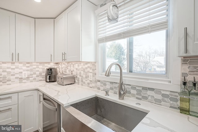 kitchen featuring sink, tasteful backsplash, white cabinetry, and light stone counters