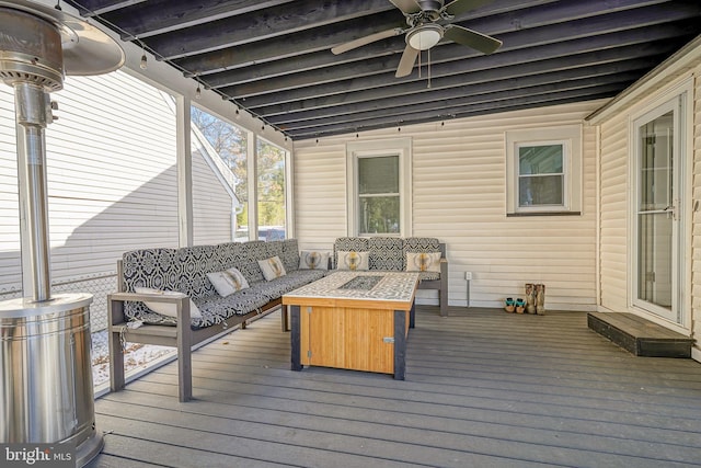 wooden terrace featuring ceiling fan and an outdoor living space with a fire pit