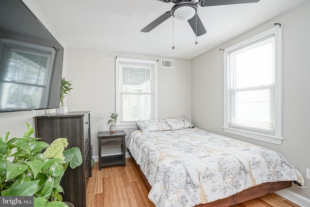 bedroom with light hardwood / wood-style floors, multiple windows, and ceiling fan