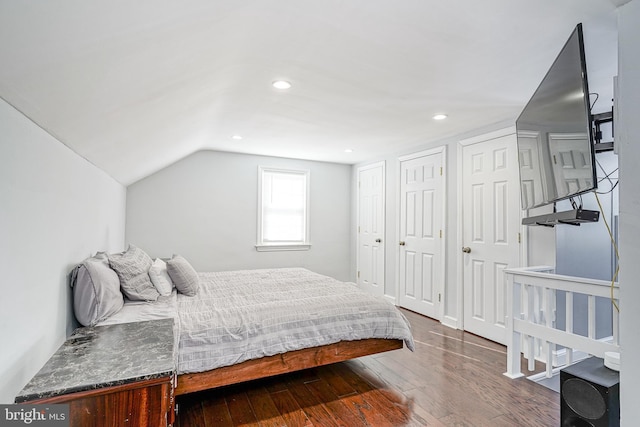 bedroom with multiple closets, dark hardwood / wood-style floors, and lofted ceiling