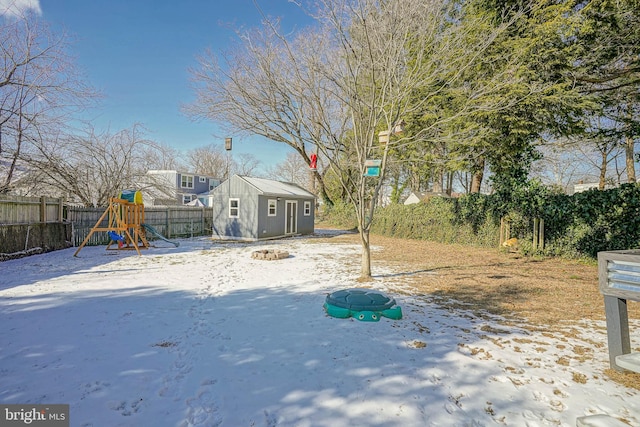 yard covered in snow featuring a playground and an outdoor structure