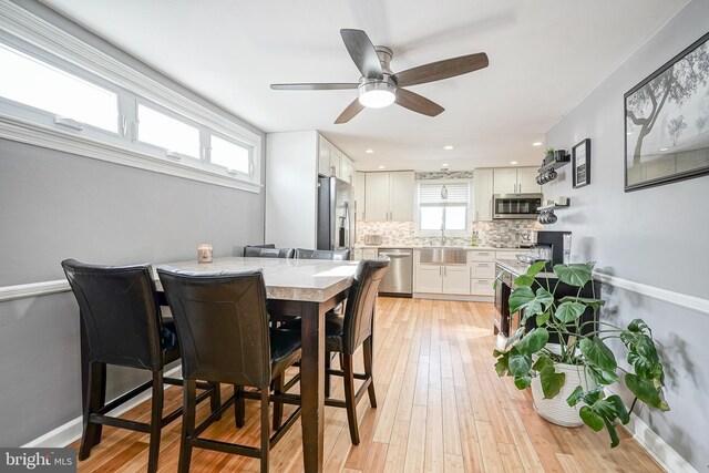 dining room with ceiling fan, sink, and light hardwood / wood-style flooring